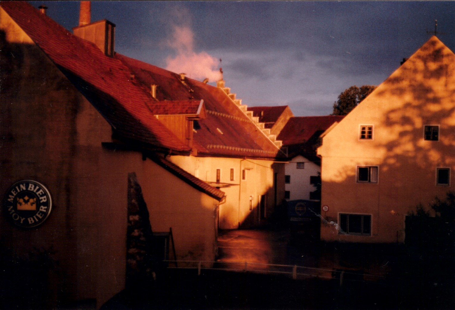 Abendlicht über den Dächern der Brauerei, an der Wand ein altes Schild Mein Bier Moy Bier
