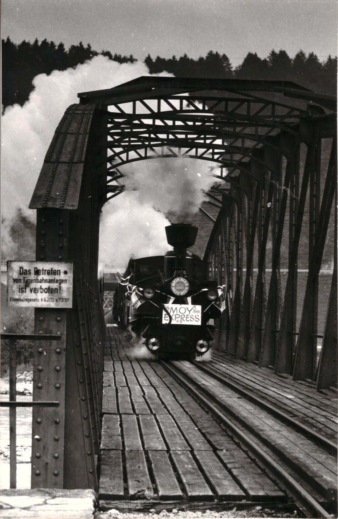 Eine Dampflok mit dem Schild Moy Express fährt über eine eiserne Brücke