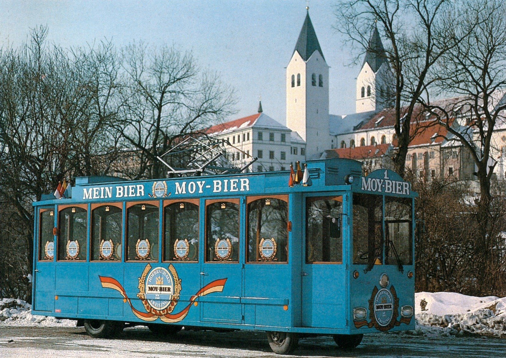 Ein blauer Wagen mit der Aufschrift Mein Bier Moy-Bier vor dem verschneiten Freisinger Domberg